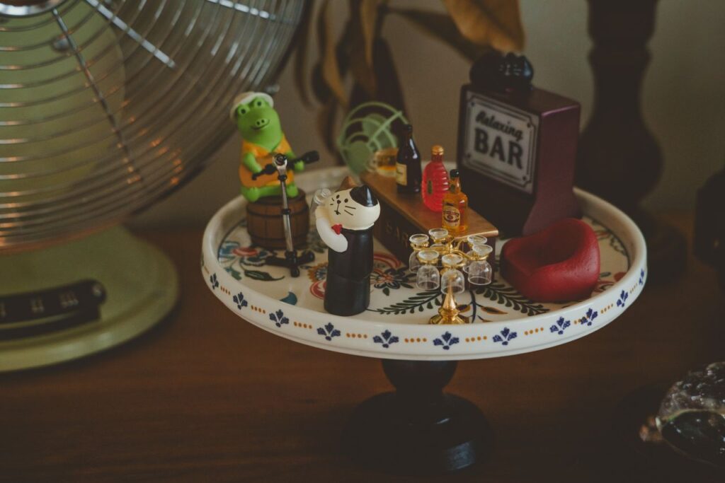 Charming miniature bar setup with playful figurines and tiny accessories on a decorative plate.