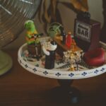 Charming miniature bar setup with playful figurines and tiny accessories on a decorative plate.