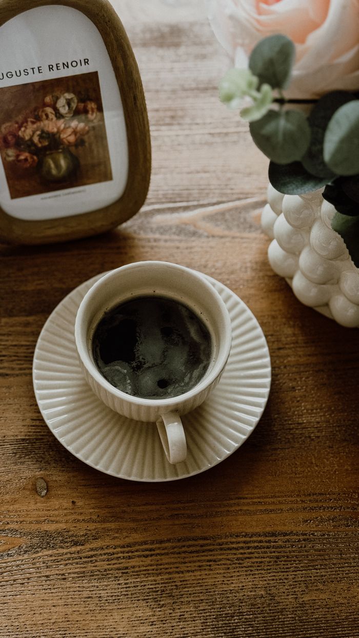 A cozy scene with a coffee cup on a rustic table, surrounded by artistic decor.