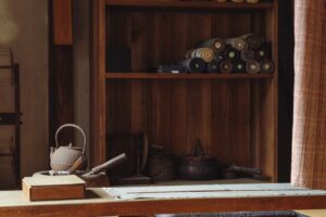 Cozy Japanese room featuring a teapot and textile rolls on wooden shelves.
