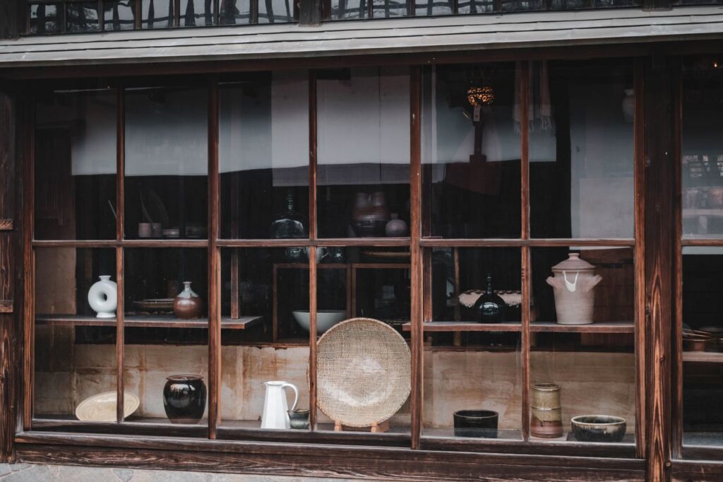 Vintage pottery displayed in a traditional Kurashiki shop window, showcasing Japanese craftsmanship.